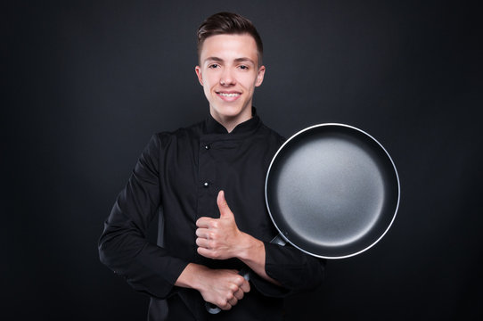 Young man chef in uniform with frying pan