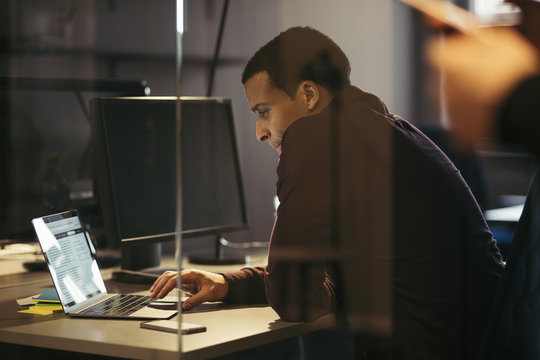 Businessman working on laptop at desk in office during night