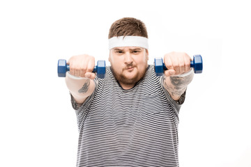 portrait of chubby man exercising with dumbbells and looking at camera isolated on white