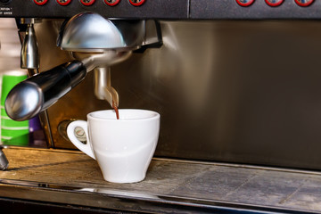 Professional espresso coffee machine makes fresh coffee and pouring it into white cup