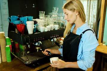 Professional barista girl makes fresh coffee for people in coffeehouse