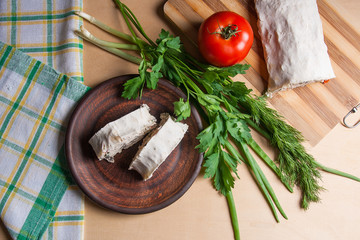 Two pieces of pita bread or lavash roll with cottage cheese or curd, chicken, tomatoes and herbs - dill, onion, parsley on brown clay plate..