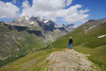 Hiker pauses to observe the mountain Tsanteleina (3601 m) in the Alps around the Iseran pass, Tarentaise Valley, Savoy, France