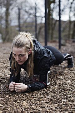 Determined female athlete performing plank position in forest