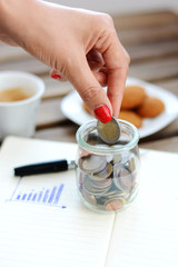Fototapeta na wymiar Money saving, hand putting coins in a jar 