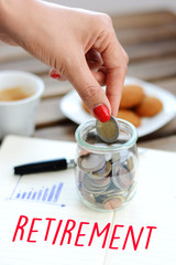 Concept of retirement planning with woman putting coins in glass jar for pension