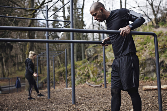 Male and female athletes standing at parallel bars in forest
