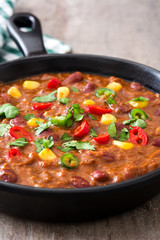 Traditional mexican tex mex chili con carne in a frying pan on wooden table
