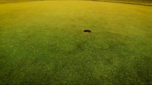 Golfplatz mit Golfball beim Einlochen 