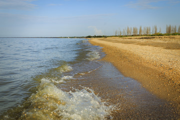 Obraz premium Waves approach the sandy beach on a sunny, clear day