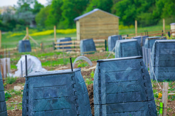 Black plastic compost bin and small wooden cabin in town garden