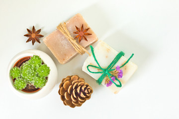 Obraz na płótnie Canvas Organic handmade soaps decoration by pinecone, star anise, dry flowers and Succulent plant on white background with copy space