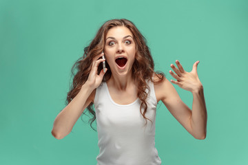 Shocked woman looking at mobile phone on green background
