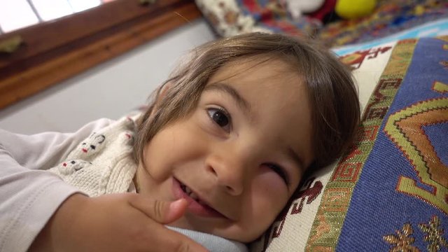 4K Comic child with a swollen eye making faces in bed