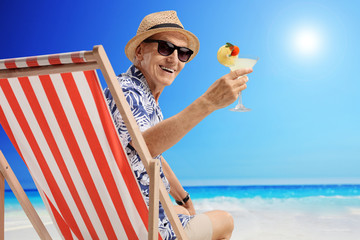 Mature man sitting in a deck chair on a beach - Powered by Adobe