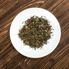Fototapeta na wymiar green tea leafs on white plate with wood background