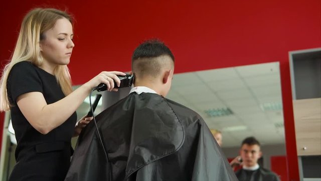A young and professional hair stylist who works in a hair salon shaves the back of the head of the client who came to change the image.
