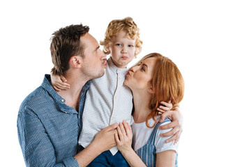 Happy parents able to kiss adorable little son isolated on white