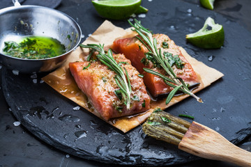 Slices of raw salmon smeared with spices and olive oil shale on a plate close-up. Preparation of...