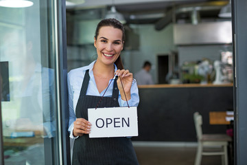 Woman holding open sign in cafe 