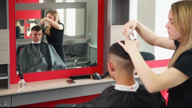 Hairdresser cuts hair for fashionable man who came to change his hair, a hair stylist cuts the unnecessary length of hair from the top to change the image