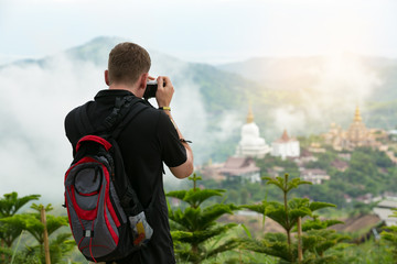 The young European tourists Taking a picture of the front view with a mountain temple. In Phetchabun Province Thailand.