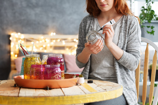Woman painting jar at home
