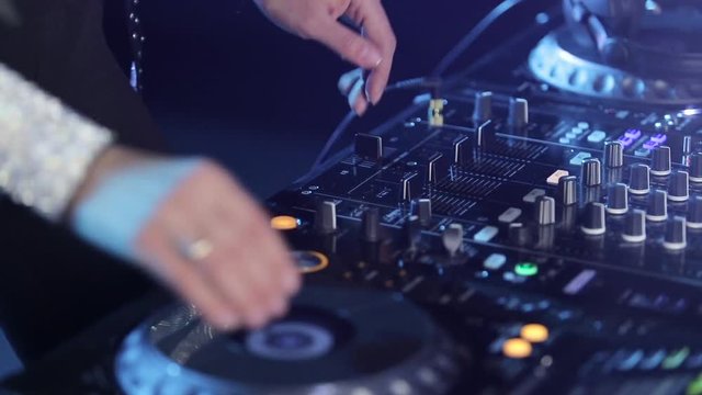 Hands of woman Dj play music on mixing console, closeups