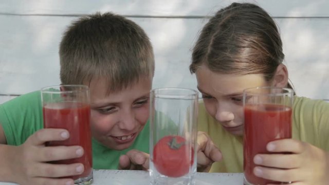 Children on a white background drink tomato juice from glasses. Two boys drink tomato juice.
