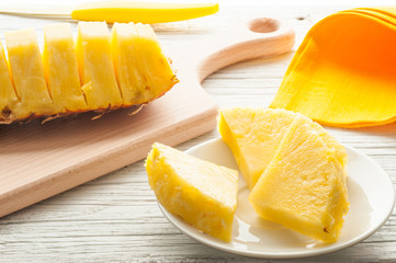 slices of a pineapple on white wooden background