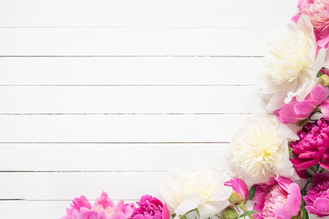 Peonies on white wooden planks background with copy space, top view. Great use as mock up for products, feminine design projects, wedding / invitation / holiday cards and so on