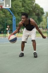 African american man on basketball court dribbling with ball. Real and authentic activity.