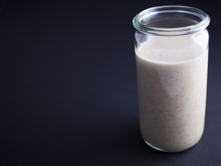 Fresh made sourdough starter in tall glass isolated on black background