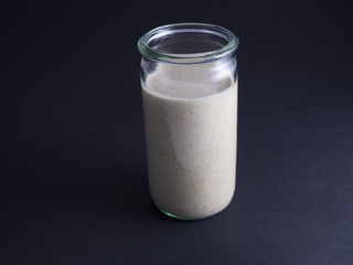 Fresh made sourdough starter in tall glass isolated on black background