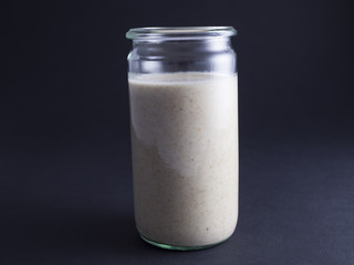 Fresh made sourdough starter in tall glass isolated on black background