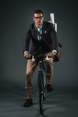 Fototapeta na wymiar confident businessman with bag riding on bicycle and looking at camera