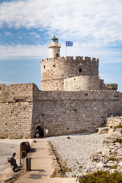 Santa Claus Fortress on the pier in Mandraki Harbor. Bastion of defense on the quay of Rhodes. A defensive building in a harbor in the town of Rhodes with a lighthouse.