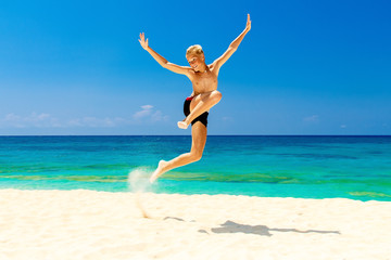 Happy teen boy having fun on the tropical beach. Summer vacation concept