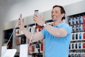 Excited male customer taking selfie with two phone at store