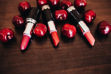 Stylish handbag with cosmetics and ripe cherries