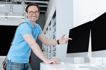 Fototapeta premium Cheerful man beaming while pointing toward personal computer