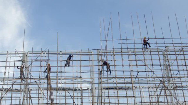 Bamboo scaffolding - Hong Kong construction worker erecting bamboo scaffolding on top of a tall building in Hong Kong.