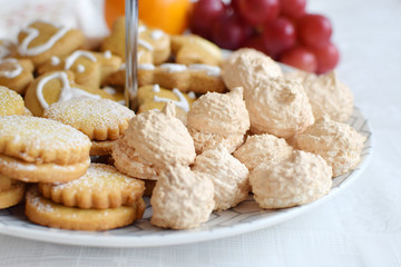 Several types of homemade pastry with coconut macaroons, filled cookies and honey cakes on a multi layer plate, selective focus