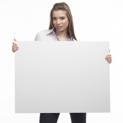 Fototapeta premium Young happy woman portrait of a confident businesswoman showing presentation, pointing placard gray background. Ideal for banners, registration forms, presentation, landings, presenting concept..