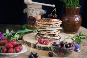 Delicious pancakes with berries on the authentic wooden stand. Summer food still life concept.