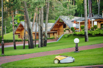 Robot lawn mower on background wooden houses