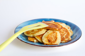 Ruddy freshly cooked pancakes lie on a blue plate on a white background.