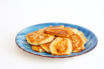 Ruddy freshly cooked pancakes lie on a blue plate on a white background.