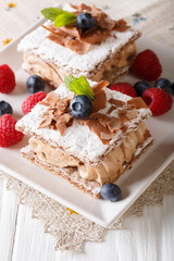 Millefeuille with coffee cream, decorated with berries and mint close-up. vertical