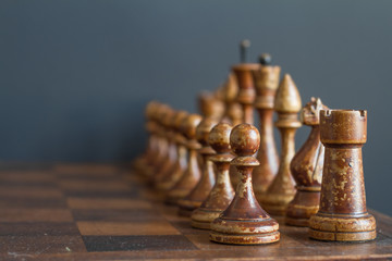 Vintage wooden chess pieces on an old chessboard.